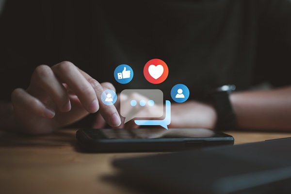 Person using a smartphone with floating social media icons above the screen, suggesting the impact of online activity on relationships or divorce proceedings. (462107702)